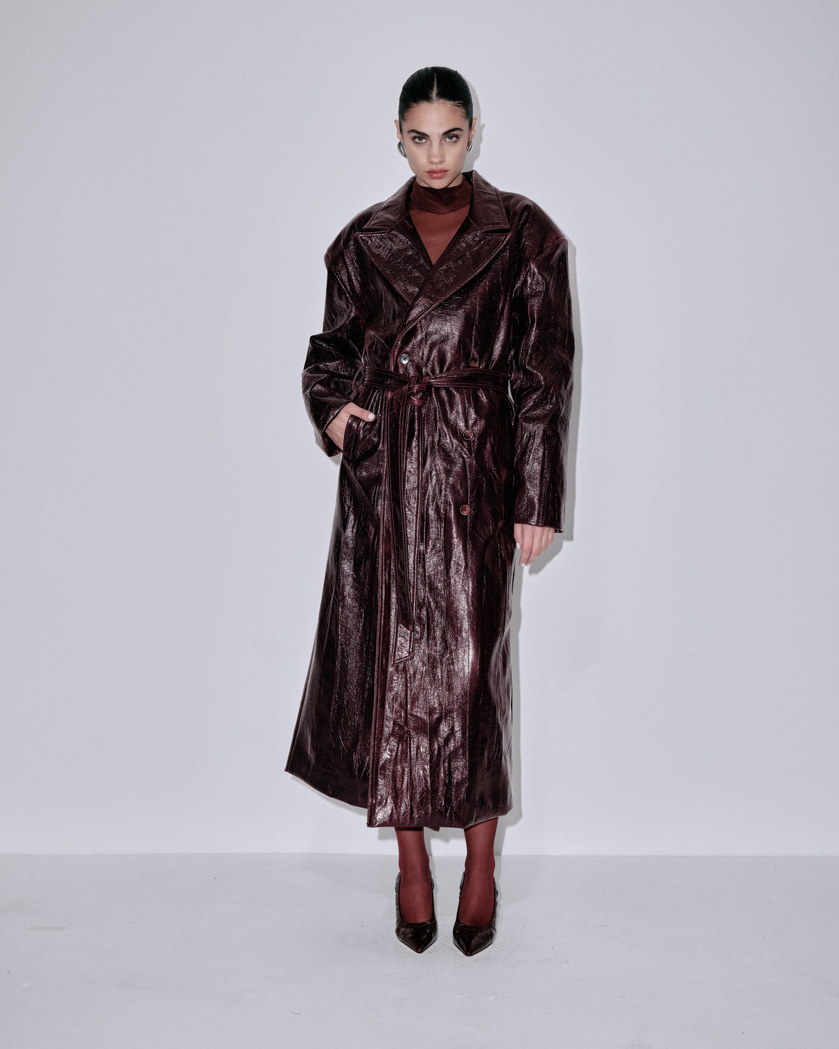 Long belted coat in dark metallic berry with notched lapels and button-front closure