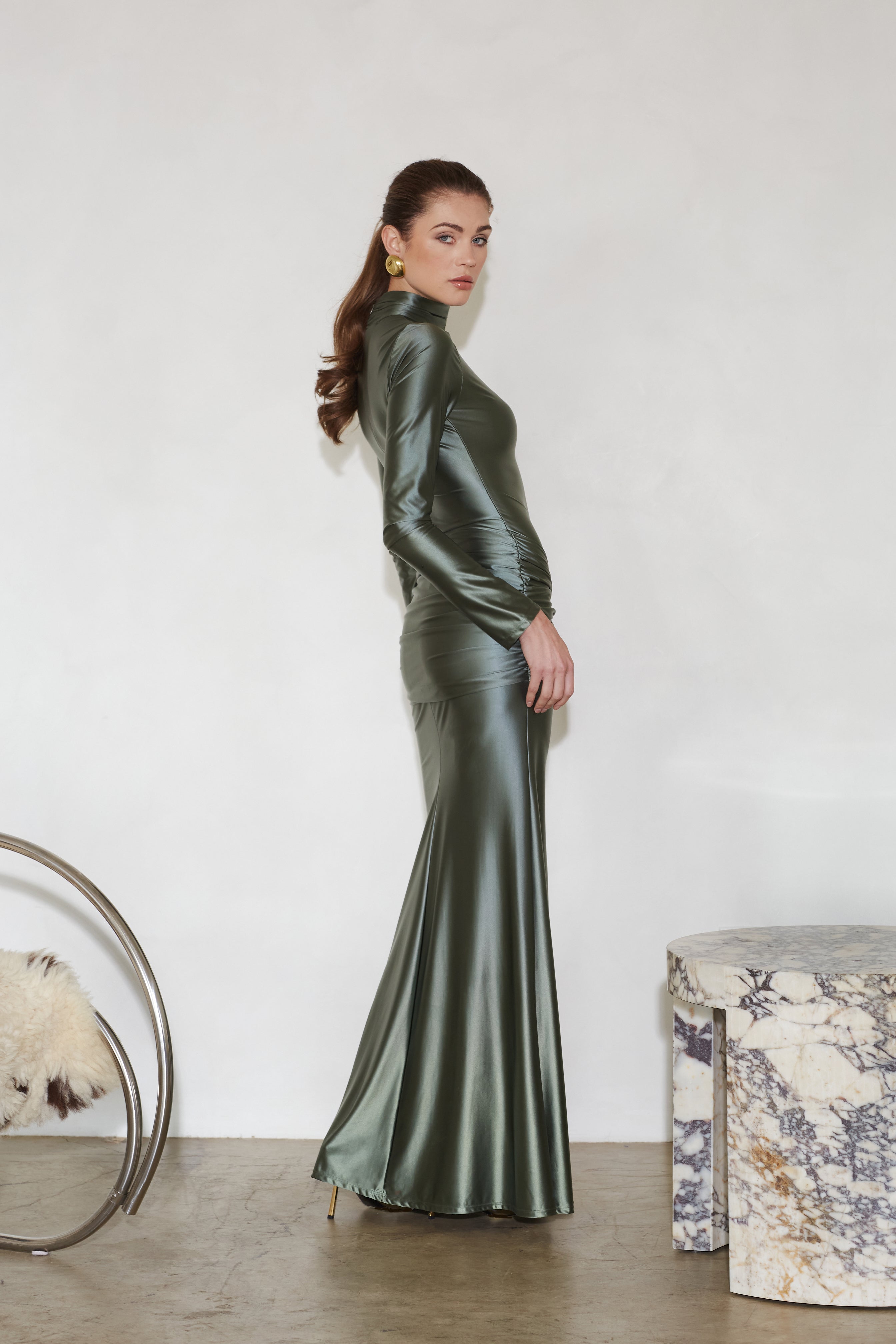 Satin maxi dress in deep green, long sleeves, fitted silhouette, side profile