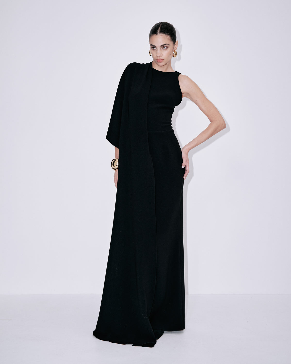 Black sleeveless maxi dress with draped shoulder overlay and defined waist seam
