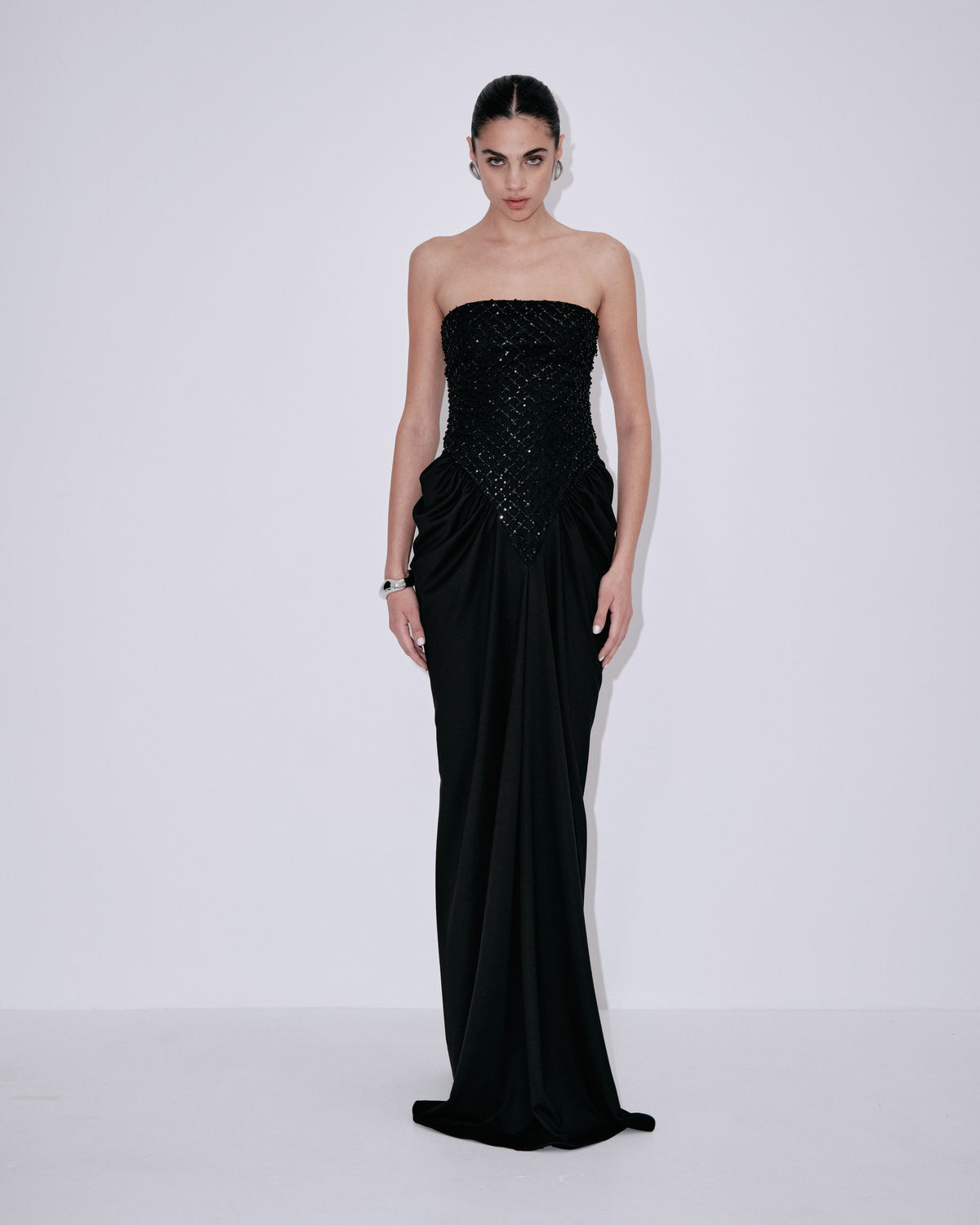 Black strapless gown with textured sequin bodice, ruched waist, and long column skirt