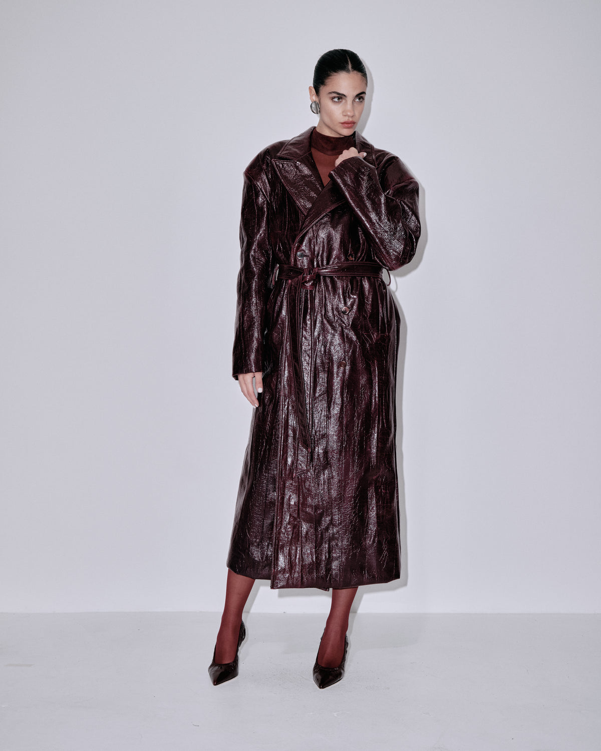 Shiny dark berry long coat with notched lapels, waist tie, and patch-style pockets