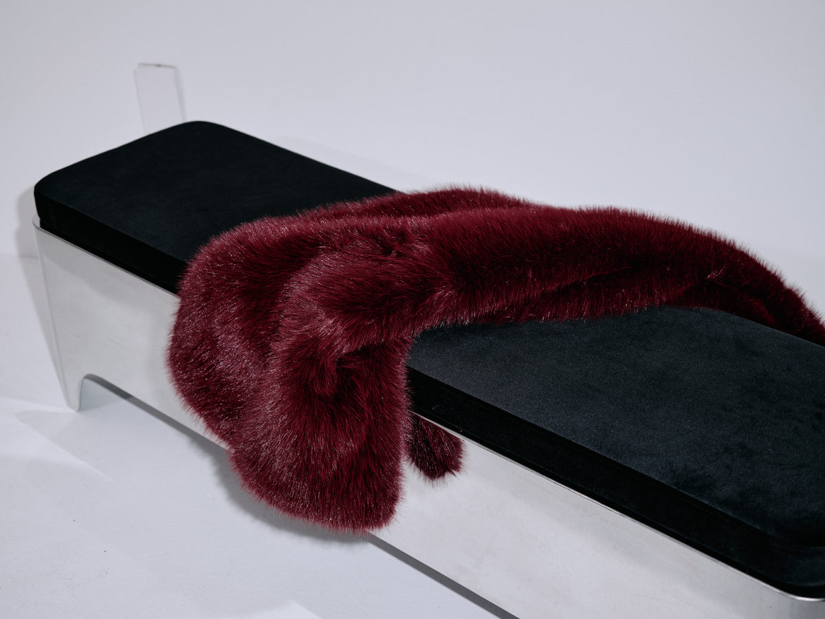 Wine fur scarf close-up on dark cushion, thick soft plush trim